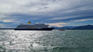 Spirit of Adventure Cruise Ship in the Bay of Santander The image shows the impressive cruise ship "Spirit of Adventure" sailing in the picturesque Bay of Santander. This majestic vessel, painted in elegant blue and white colors with yellow accents, stands out in the bay's silvery water, reflecting the sunlight on a partly cloudy day. In the scene, a small tugboat escorts the cruise ship, providing an interesting contrast with the calm mountains rising on the horizon. The Bay of Santander, known for its natural beauty and strategic location, offers a spectacular setting for cruise navigation. The light of dawn or dusk adds a special shine to the water, creating a visual effect that highlights the grandeur of the "Spirit of Adventure." This corner of Cantabria is not only a key point for maritime tourism but also an attractive destination for lovers of coastal landscapes and navigation.